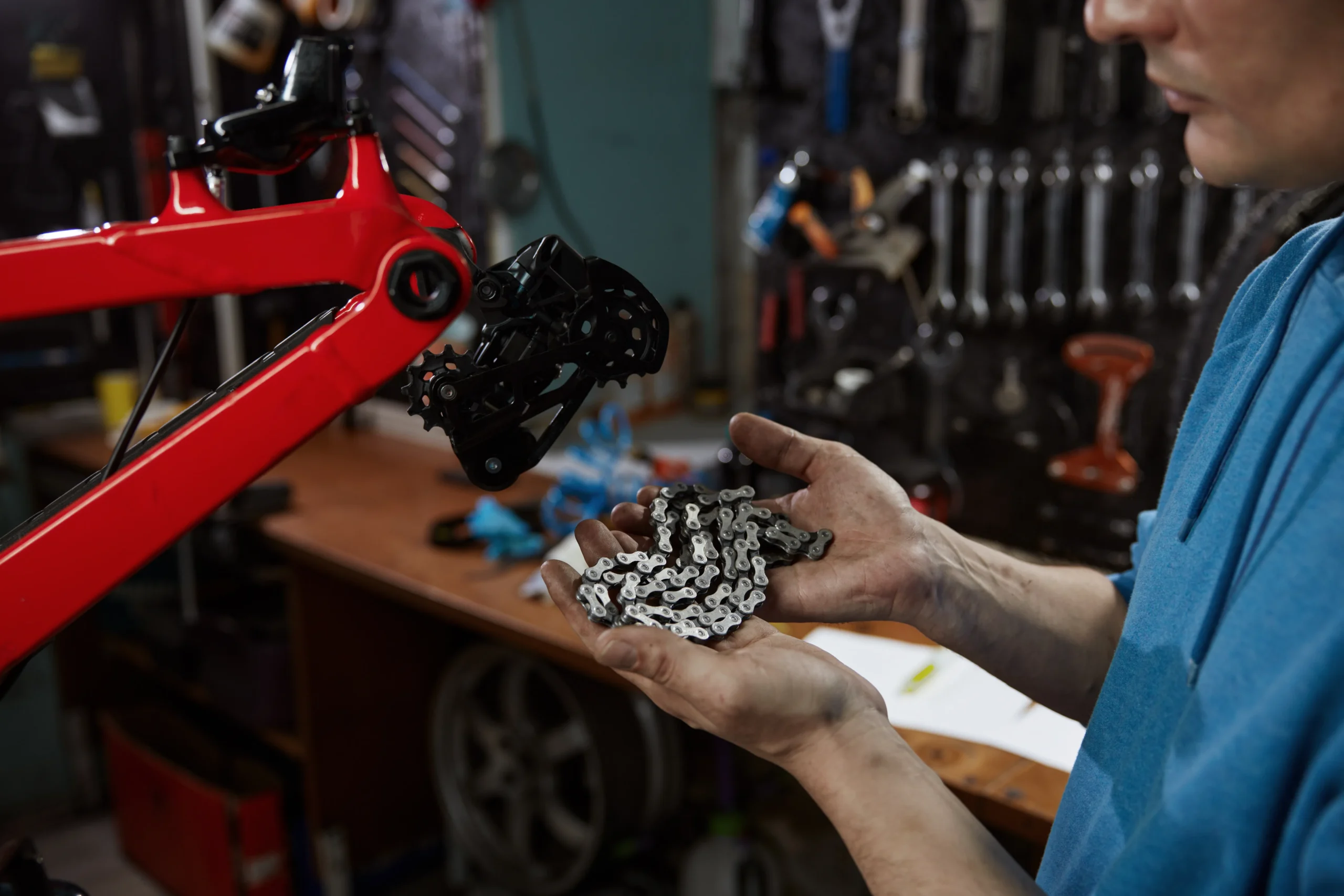 Mechanic holding a new chain, replacing bike parts with original components in the shop.